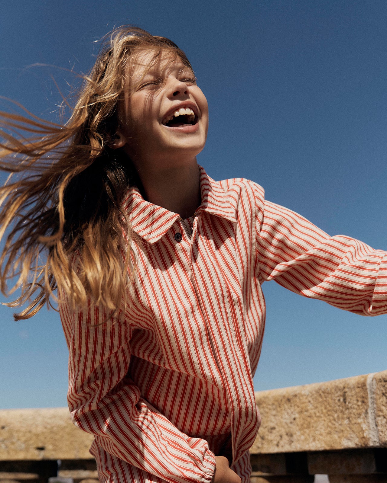 Person wearing a red and white striped shirt against a clear blue sky