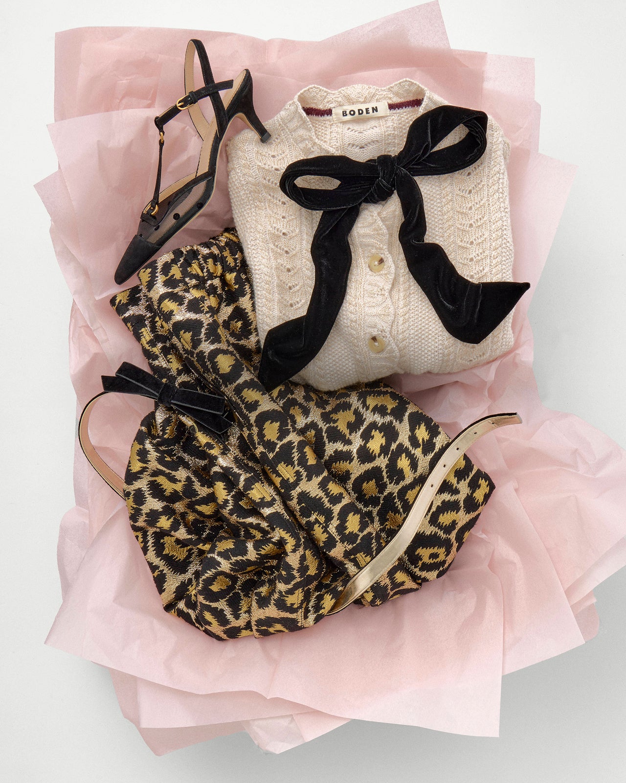 Leopard print shoes and beige cardigan with black bow on pink fabric