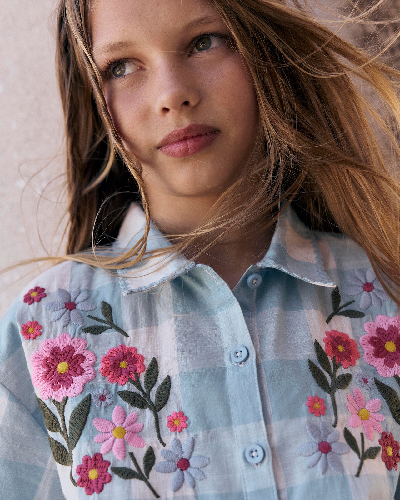 Young girl wearing a floral embroidered shirt with a soft background