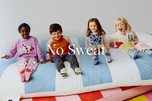 Four children sitting on a colorful bed with a 'No Sweat' text overlay.