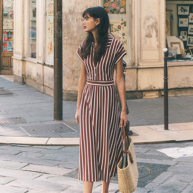 Woman in a striped dress standing on a street in an urban setting
