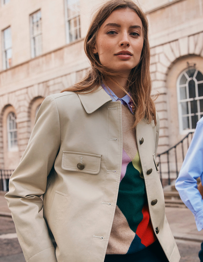 Woman wearing a beige trench coat standing in front of a building
