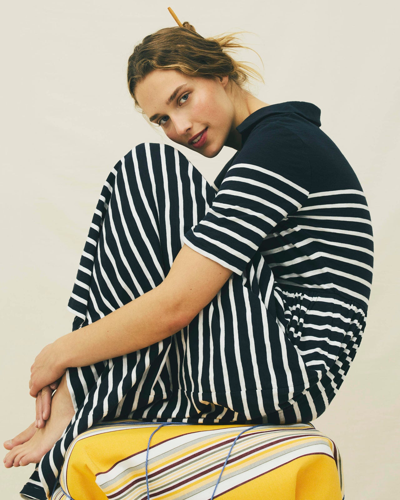 Person wearing a black and white striped shirt with yellow pants on a plain background