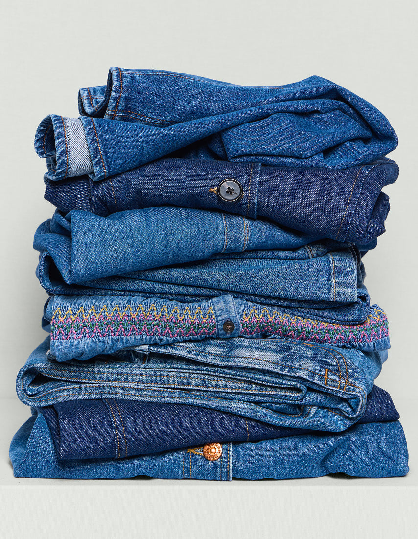 Stack of folded blue jeans on a light gray background