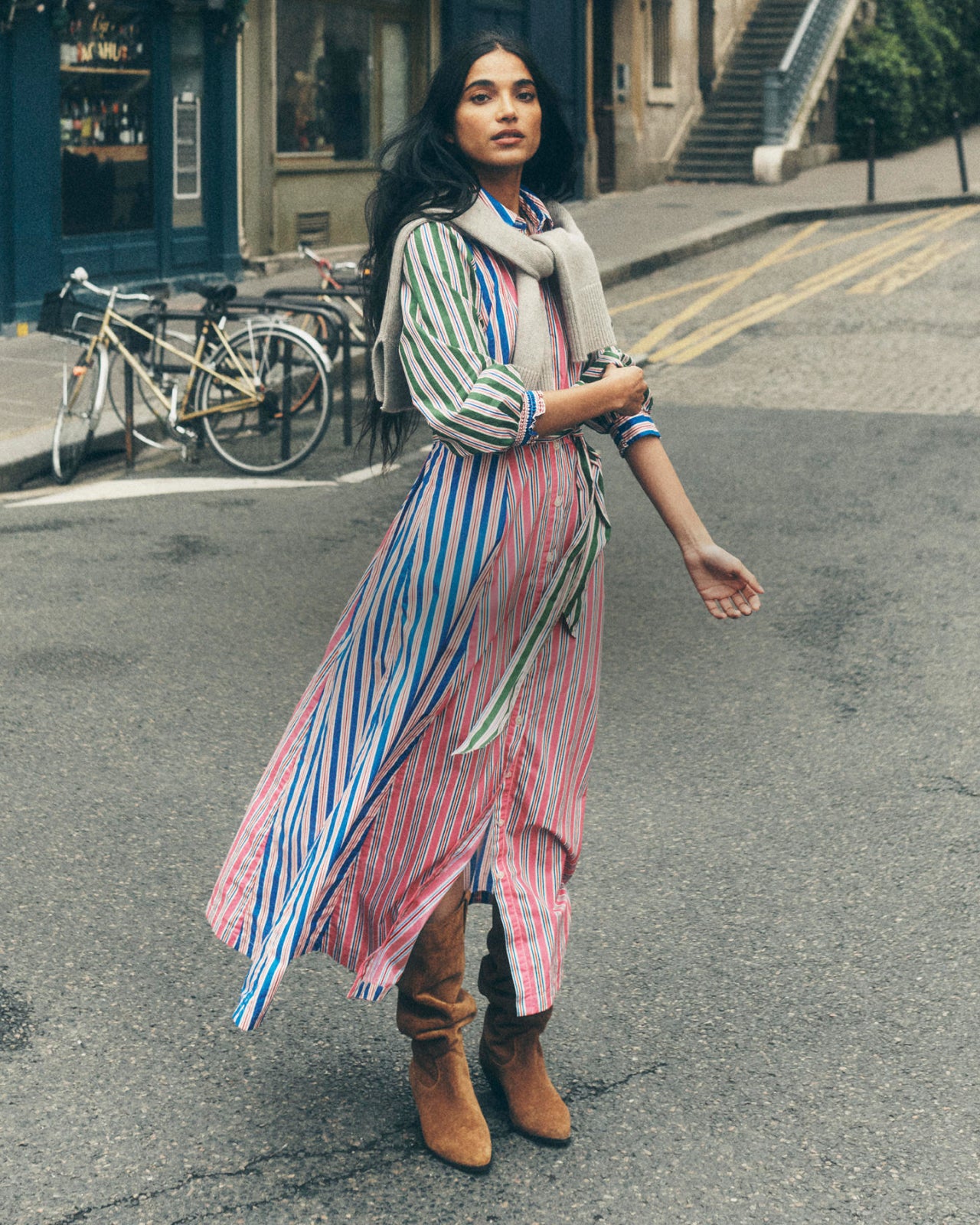 Woman standing in the street wearing a coourful striped Boden dress.