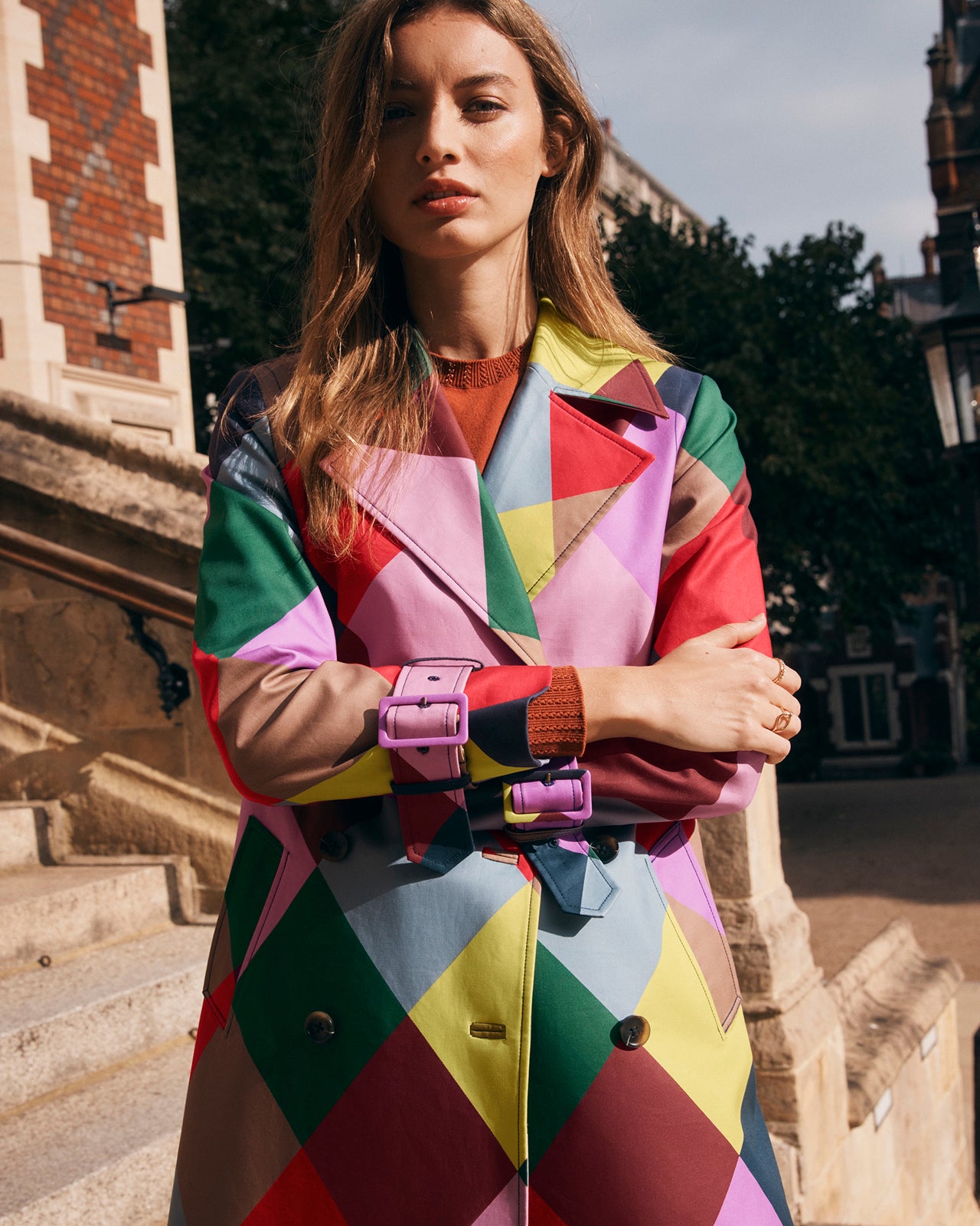 Woman wearing a colorful geometric-patterned coat outdoors.