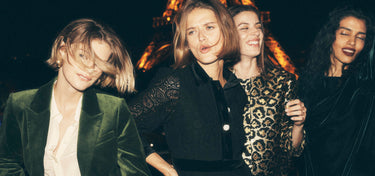 Four women standing close together with a dark background