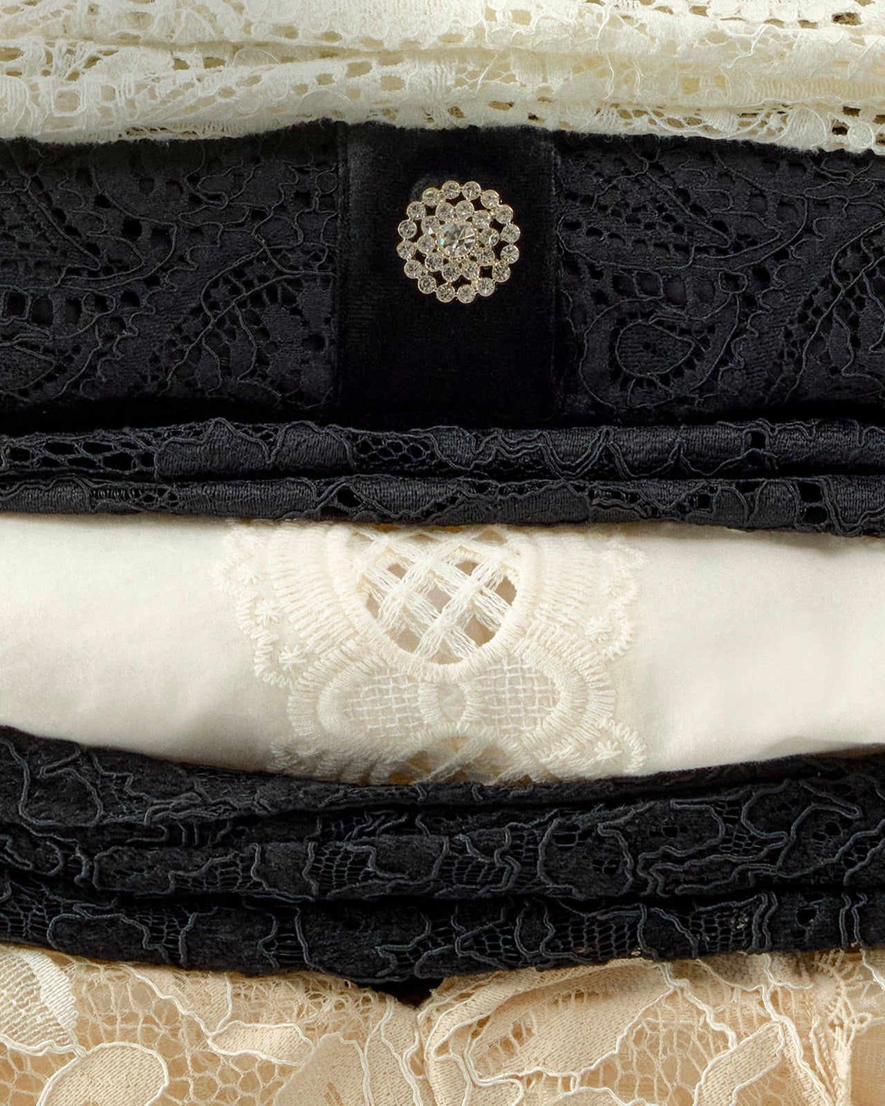 Stack of black and white lace fabrics with a decorative button.