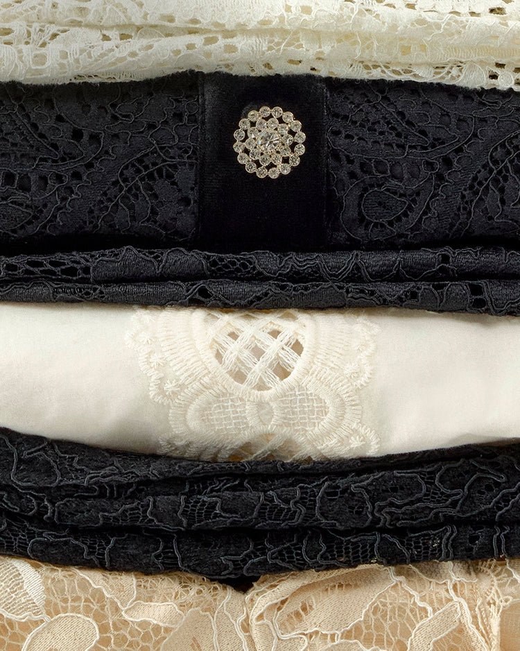 Stack of black and white lace fabrics with a decorative button.